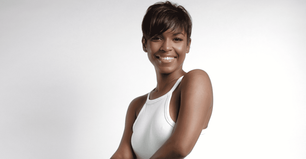 A black-haired woman in a white tank top posing for a photo.