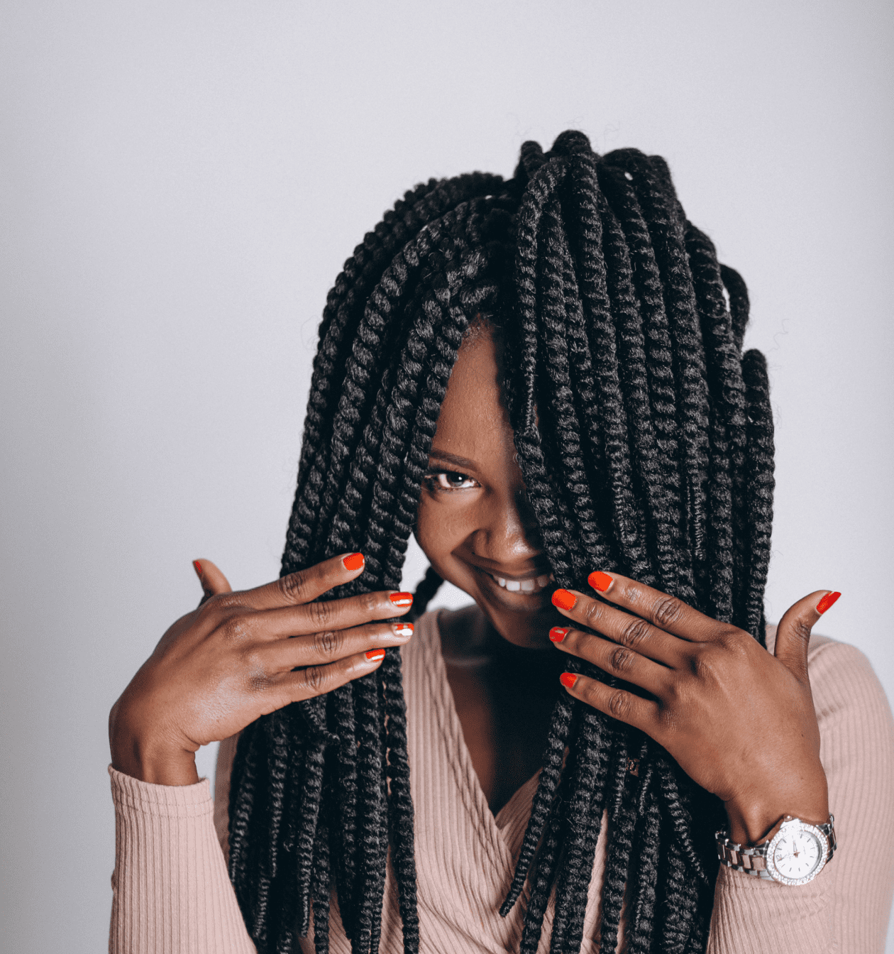 A Black hair stylist with braided hair covering her face.