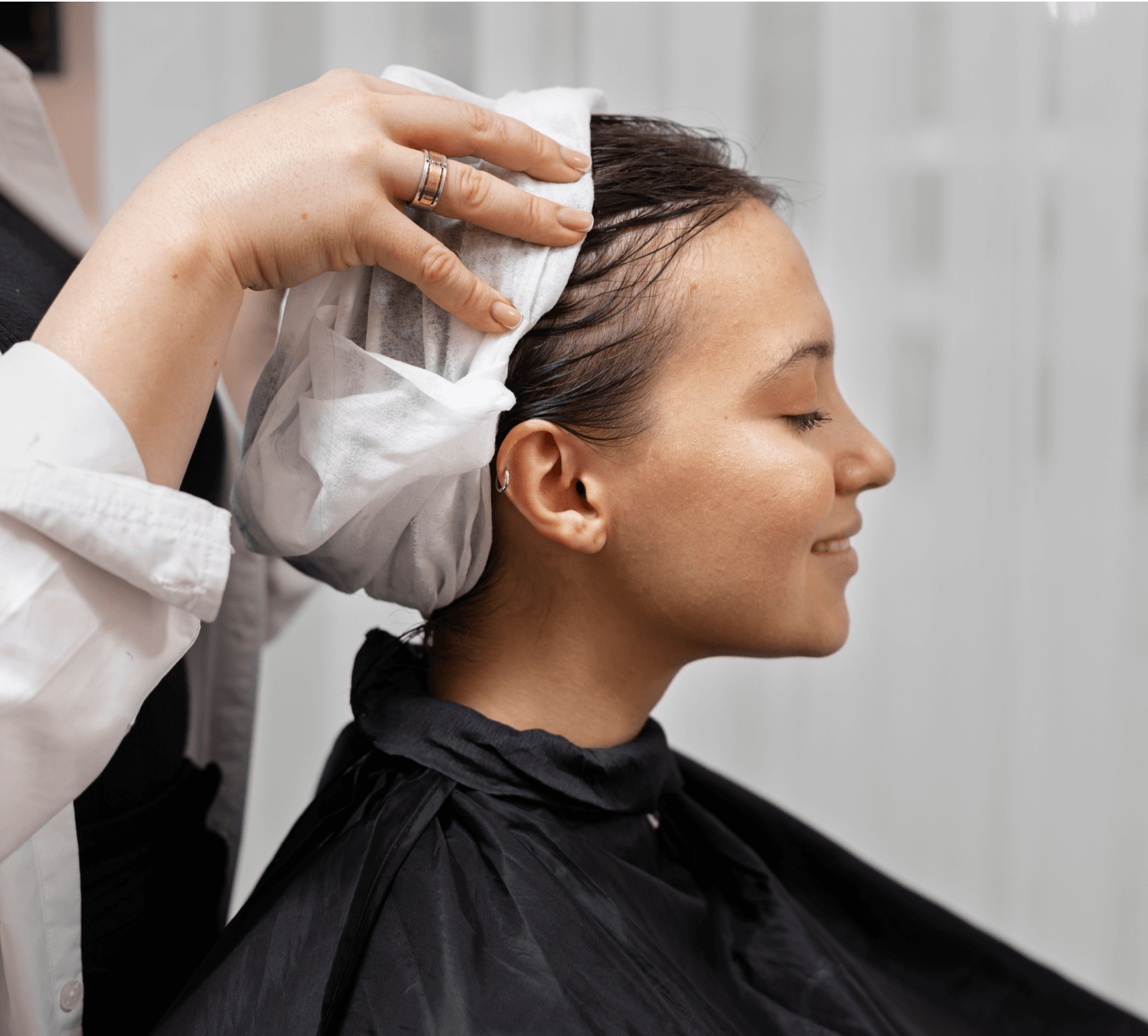 A black hairstylist is cutting a woman's hair.