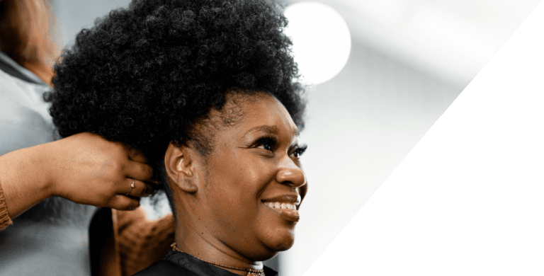 A woman is getting her hair done by a Black stylist.