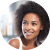 A black woman hairstylist with afro hair smiling in a circle.